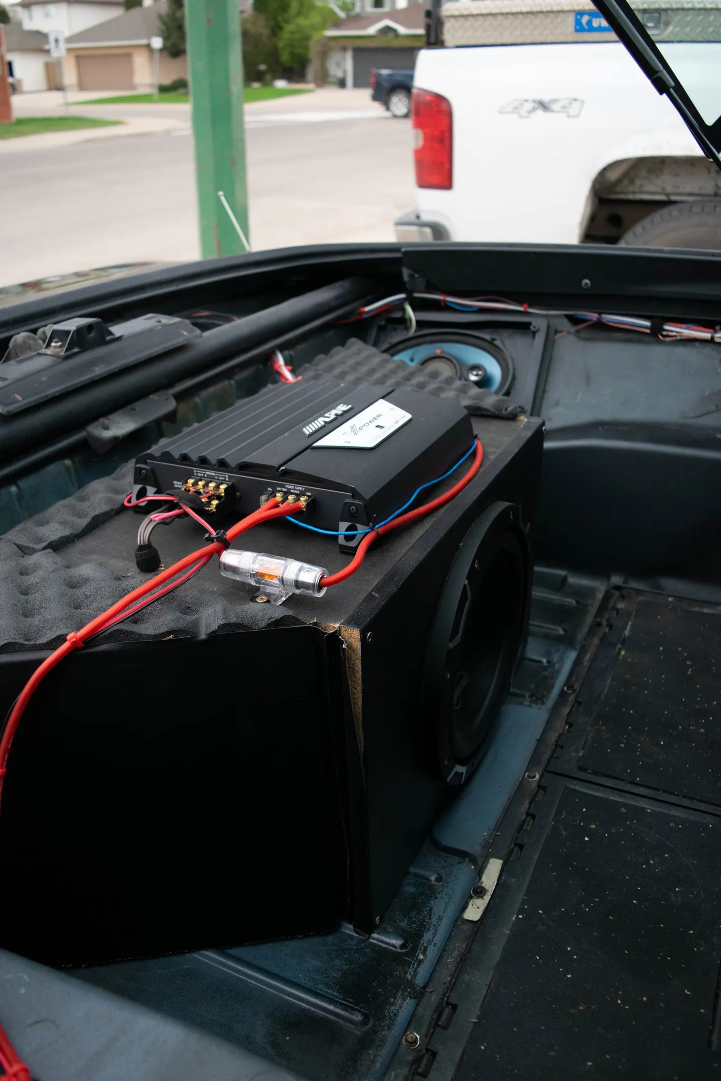 The audio rebuild — Alpine amp, custom subwoofer enclosure, inline fuse, and sound-deadening foam in the rear compartment